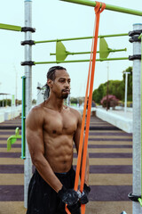 Man exercising triceps with elastic band in outdoor park