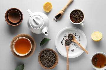 Composition with tea pot, bowls and dry tea leaves on white background