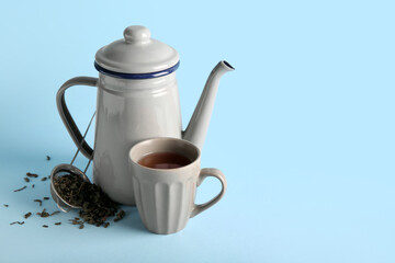 Stylish tea pot, cup of tea and strainer on blue background
