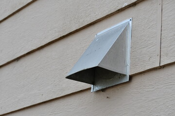 Dryer vent poking through vinyl siding.