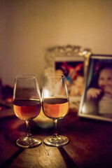 Two Glasses of Wine in Candlelit Setting with Blurred Family Portraits