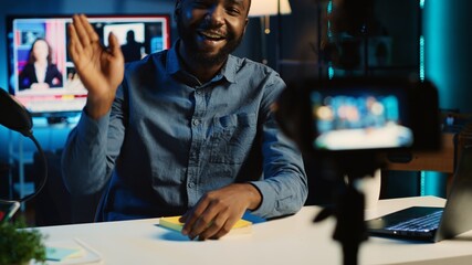 African american content creator films video review of book, presenting synopsis to audience and giving feedback. Internet star sponsored by publisher to show new novel release to subscribers