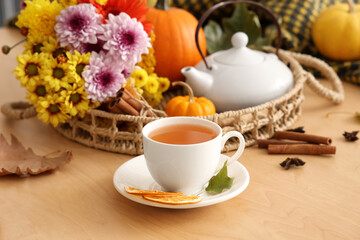 Tea pot, cup of hot green tea, pumpkins and autumn leaves on table