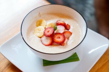 delicious and organic bowl of oatmeal with colorful strawberries and bananas at healthy restaurant in south american city with fresh fruit