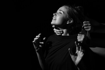 Many hands stretched to young crying woman on dark background