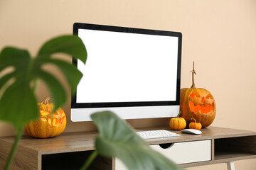 Workplace with modern computer and pumpkins in stylish office decorated for Halloween celebration