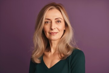 Fototapeta premium Mature woman with stylish casual attire poses on bright green background. Middle-aged female model wears fashionable dress, has elegant make-up. Confident lady with pretty smile, attractive features.