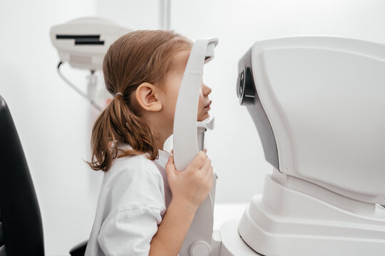 In a modern ophthalmology clinic, an ophthalmologist checks a little girl's vision using a binocular slit lamp. Advertisement for pediatric ophthalmology