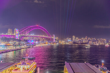 Obraz premium Colourful Light show at night on Sydney Harbour NSW Australia. The bridge illuminated with lasers and neon coloured lights for the Sydney Vivid light show