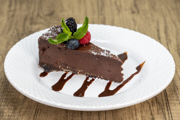 Slice of bitter sweet chocolate cake with fruit topping and chocolate garnishment for dessert