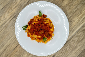 Overhead view of pappardelle pasta served with lamb ragu sauce is cooked to perfection