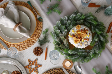 Christmas table setting with cake, wreath, pine cones and burning candles