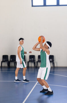 Playing basketball, two players in uniform practicing on indoor court, copy space