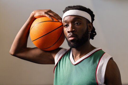 Holding basketball, athlete in sports jersey and headband posing confidently