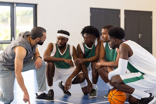 Basketball coach giving strategy to team players on court during practice