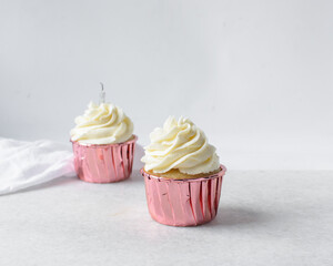 Pink cupcakes with tall buttercream swirl, cupcakes in pink foil liners with vanilla buttercream, frosted cupcakes on a white background
