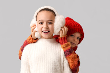 Cute little happy children in warm winter clothes on grey background