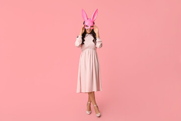 Beautiful young happy Asian woman in bunny mask on pink background