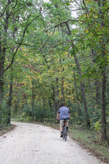 Fototapeta premium Overweight man riding a bicycle in autumn on the Des Plaines River Trail in Libertyville, Illinois