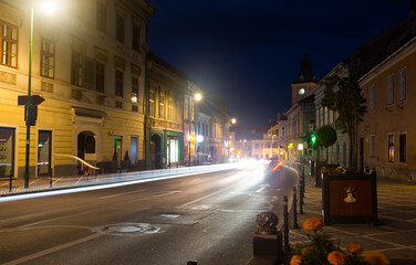 Naklejka premium View of illuminated Brasov streets with clock tower of city Council at night