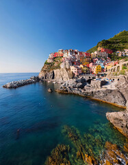 Naklejka premium Colorful cliffside village overlooking serene sea with boats