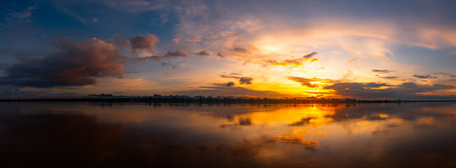 Panorama Reflection of vivid sunset sky reflection in water.Colorful sunrise with Clouds over Mekong River , Nakhon Phanom  province,Thailand,ASIA.