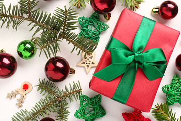 Gift box with Christmas balls, fir tree branches and decorative stars on white background