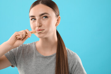 Obraz premium Beautiful woman brushing her teeth on light blue background, space for text