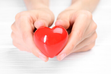 Fototapeta premium Woman holding red heart at white wooden table, closeup