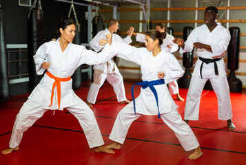 Fototapeta premium Man and woman in pairs exercising karate movements during group training