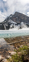 Incredible nature views at Lake Louise in world famous Alberta during spring time with partially frozen lake. Turquoise, aqua water colour showing through layer of ice on water surface. 