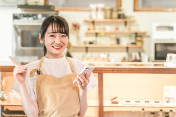 カフェ・レストラン・飲食店で働くウェイトレス・ホールスタッフをする女性（スマホ・モバイルオーダー）
