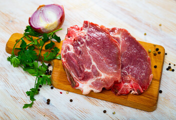 Fototapeta premium Sliced raw pork chop with parsley and onion