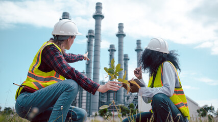 Engineers wear safety gear inspecting or document related to plants environment features large...
