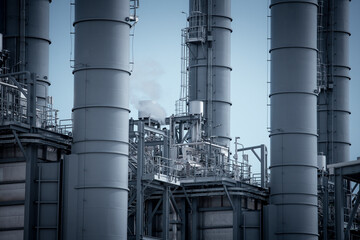 Engineers wearing safety gear, including hard hats examining survey a large blueprint tablet standing industrial facility gas or oil refinery engaged in a job requires high safety standards concept