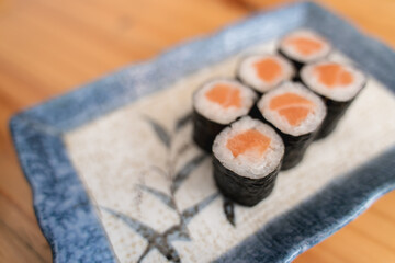 Six pieces of salmon maki sushi on a decorative plate.