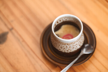 Cup of savory soup served in a traditional ceramic bowl with a spoon on a wooden table.