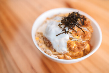 Katsudon, a Japanese rice bowl topped with breaded pork cutlet, egg, and seaweed, served in a bowl.