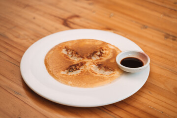 Japanese rice flour pancake with syrup on a white plate, divided into eight sections.