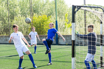 Heading the ball towards the goal. Football match between two youth teams
