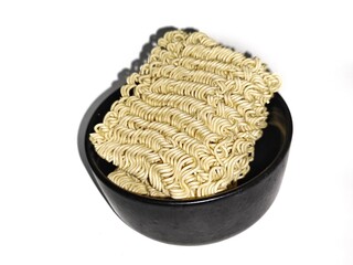 Uncooked instant noodles in a black bowl on a white background