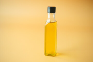 A Clear Glass Bottle filled with Cooking Oil set against a Bright Yellow Background