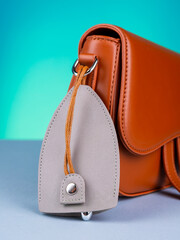 Close up of gray  leather key holder with keys on fashionable brown bag