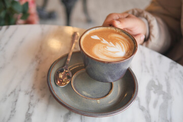 An Artistic Coffee Cup is elegantly placed on a Marble Table, accompanied by a Spoon
