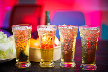 A cold beer glass sits on a cluttered desk during a late-night party, its golden hue reflecting the dim lighting, creating a relaxed atmosphere for unwinding, put on black wooden desk