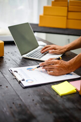 close-up of a man's hands working meticulously with a cardboard box on wooden desk, representing an online seller effort to pack products, successful business operations and customer satisfaction.
