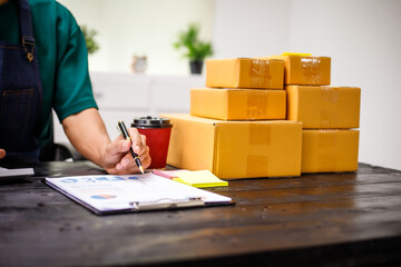 close-up of a man's hands working meticulously with a cardboard box on wooden desk, representing an...