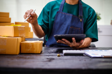 close-up of a man's hands working meticulously with a cardboard box on wooden desk, representing an...