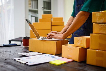 close-up of a man's hands working meticulously with a cardboard box on wooden desk, representing an online seller effort to pack products, successful business operations and customer satisfaction.