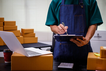 close-up of a man's hands working meticulously with a cardboard box on wooden desk, representing an...